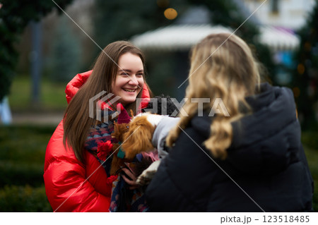 Young women enjoying time outdoors while caring for small dogs on a chilly day 123518485