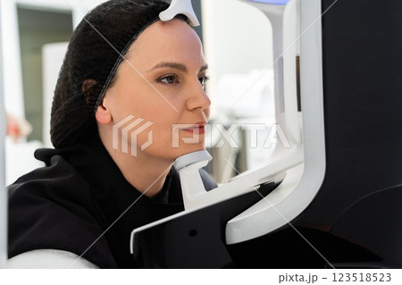 Woman undergoing eye examination at a modern eye clinic in bright setting Woman undergoing eye examination at a modern eye clinic in bright setting 123518523