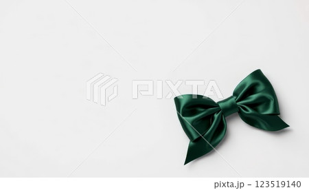 A luxurious green satin bow laid flat against a neutral background, symbolizing elegance, perfect for gift wrapping and special occasions. 123519140