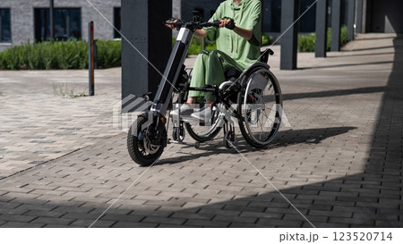 A woman controls a wheelchair using a special manual device. Close-up of female hands on electric handbike.  A woman controls a wheelchair using a special manual device. Close-up of female hands on electric handbike.  123520714
