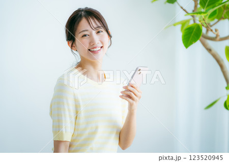 部屋でスマホを操作する女性 123520945