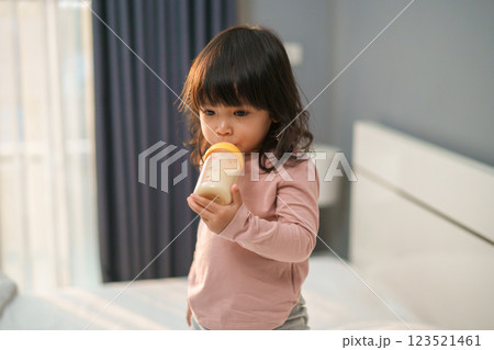 toddler girl drinking milk from bottle on bed toddler girl drinking milk from bottle on bed 123521461