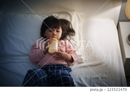 toddler baby girl drinking milk from bottle on bed at night 123521470
