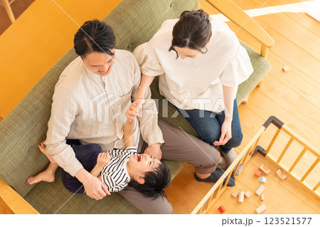リビングで遊ぶ子供と若い夫婦 リビングで遊ぶ子供と若い夫婦 123521577