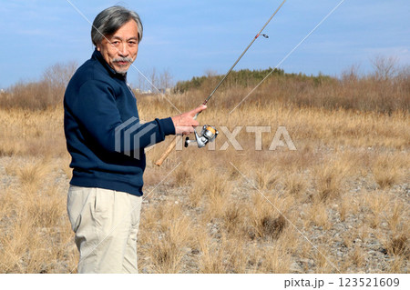 広い河川敷を歩いて流れに向かうベテラン釣り師 広い河川敷を歩いて流れに向かうベテラン釣り師 123521609