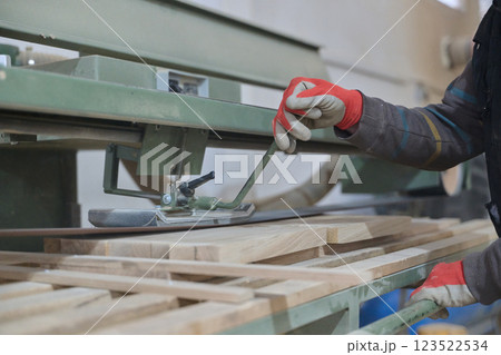Close Up of Worker Carefully Cutting and Planing Wooden Pieces for Furniture in Wood Industry 123522534