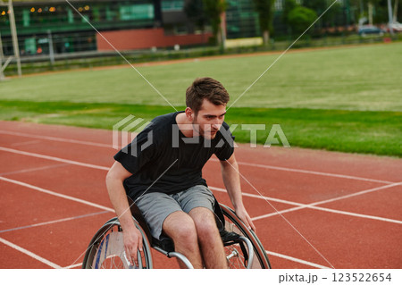 A person athlete with disability in a wheelchair racing on an outdoor track. 123522654