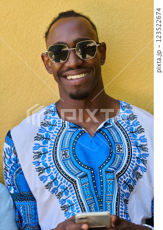 African American Teenager in Traditional Sudanese Attire Engaged with Smartphone 123522674