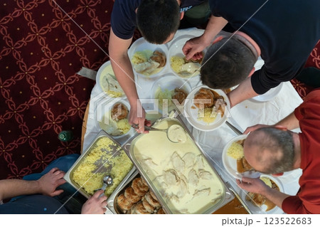 Top view of people serving food at a Mosque a communal meal during Ramadan before breaking the fast on Iftar dinner. Warm festive atmosphere celebrating Ramadan Karim and Eid, the Islamic holy month 123522683