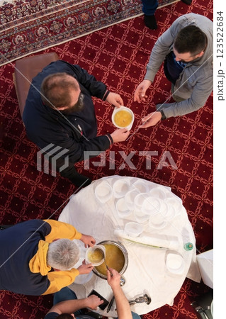 Top view of people serving food at a Mosque a communal meal during Ramadan before breaking the fast on Iftar dinner. Warm festive atmosphere celebrating Ramadan Karim and Eid, the Islamic holy month Top view of people serving food at a Mosque a communal meal during Ramadan before breaking the fast on Iftar dinner. Warm festive atmosphere celebrating Ramadan Karim and Eid, the Islamic holy month 123522684