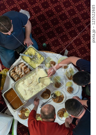 Top view of people serving food at a Mosque a communal meal during Ramadan before breaking the fast on Iftar dinner. Warm festive atmosphere celebrating Ramadan Karim and Eid, the Islamic holy month 123522685
