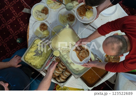 Top view of people serving food at a Mosque a communal meal during Ramadan before breaking the fast on Iftar dinner. Warm festive atmosphere celebrating Ramadan Karim and Eid, the Islamic holy month 123522689