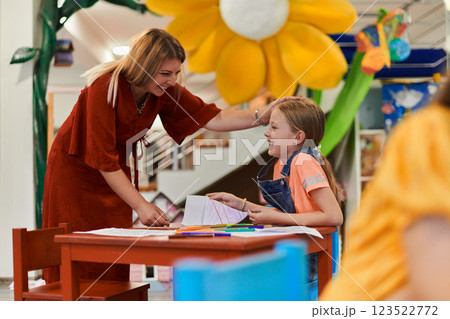Creative kids during an art class in a daycare center or elementary school classroom drawing with female teacher. Creative kids during an art class in a daycare center or elementary school classroom drawing with female teacher. 123522772