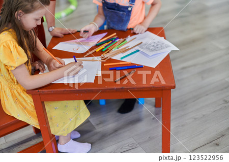 Creative kids during an art class in a daycare center or elementary school classroom drawing with female teacher. 123522956