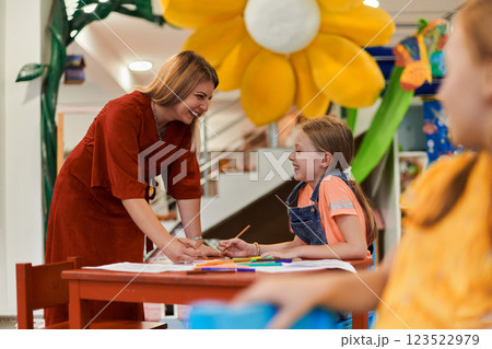 Creative kids during an art class in a daycare center or elementary school classroom drawing with female teacher. 123522979
