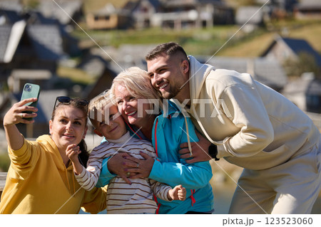 Radiant with joy, a happy family captures precious moments in nature as they share smiles and laughter while taking a selfie with a smartphone, creating cherished memories against the backdrop of the Radiant with joy, a happy family captures precious moments in nature as they share smiles and laughter while taking a selfie with a smartphone, creating cherished memories against the backdrop of the 123523060