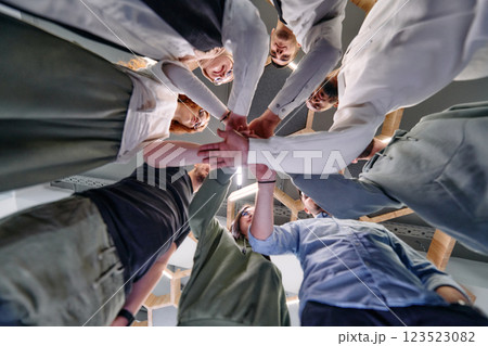 A group of young businessmen offer their hands together, symbolizing togetherness in the business world A group of young businessmen offer their hands together, symbolizing togetherness in the business world 123523082