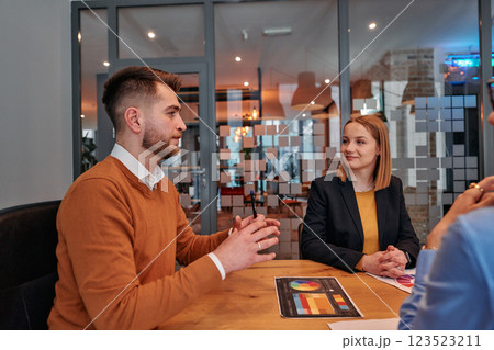 In the vibrant ambiance of a modern startup office, a diverse team of business professionals engage in discussions on various projects and develop new business strategies, epitomizing creativity and 123523211
