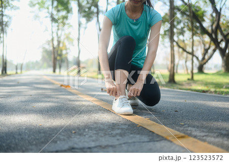 Close up of athlete tying her shoelaces before outdoor run on park trail Close up of athlete tying her shoelaces before outdoor run on park trail 123523572