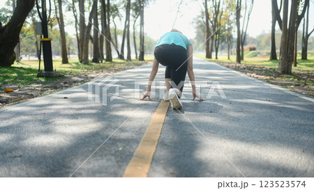 Sporty woman crouching down in starting position ready for sprint Sporty woman crouching down in starting position ready for sprint 123523574