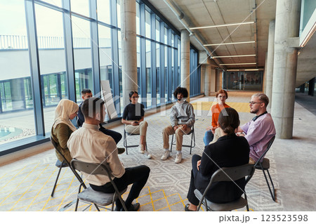 A diverse group of young business entrepreneurs gathered in a circle for a meeting, discussing corporate challenges and innovative solutions within the modern confines of a large corporation 123523598