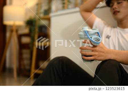 Young man taking a break after workout holding a protein shake in his hand 123523615