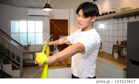 Young man athlete exercising with resistance band at home Young man athlete exercising with resistance band at home 123523617