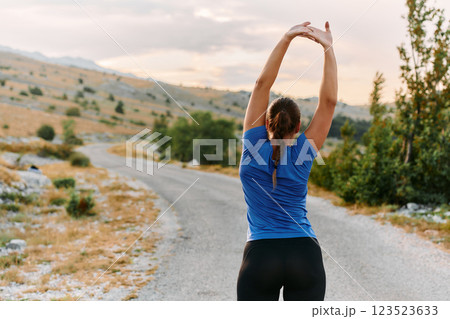 Determined Female Athlete Stretching After an Intense Run Through Rugged Mountain Terrain. 123523633