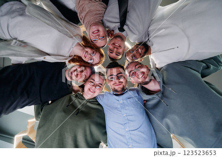 In a modern office, a group of young business professionals is captured in a warm and embracing hug, reflecting the spirit of unity, collaboration, and shared success in their dynamic workplace. 123523653