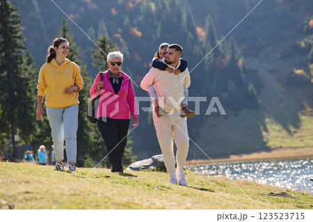 A family shares delightful moments with their friends amid the stunning landscapes of mountains, lakes, and winding paths, promoting a healthy lifestyle and the joy of familial bonds in the embrace of 123523715