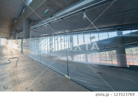 A captivating view of a modern business building under construction, showcasing its raw industrial interior with exposed steel beams and concrete walls bathed in the warm, golden hues of a sunset A captivating view of a modern business building under construction, showcasing its raw industrial interior with exposed steel beams and concrete walls bathed in the warm, golden hues of a sunset 123523769