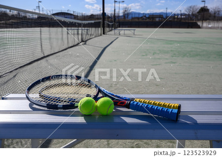 テニスコート内のベンチに置かれたラケットとボール 123523929