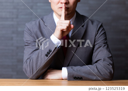 グレーのスーツを着て口に指を当てるミドル男性ビジネスマン グレーのスーツを着て口に指を当てるミドル男性ビジネスマン 123525319
