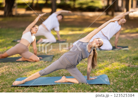 Woman participating in outdoor group yoga session in city park 123525384