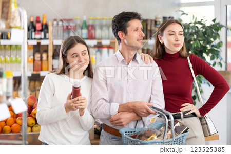 In store, family with purchases in hands looking for something on shelf of showcase In store, family with purchases in hands looking for something on shelf of showcase 123525385