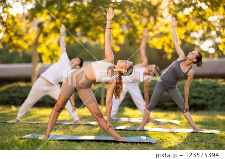 Girl participating in outdoor group yoga session in summer park 123525394