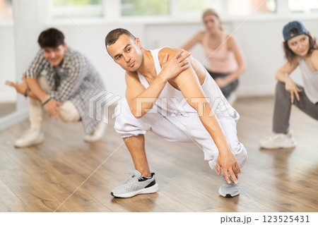 Teacher and her students squatting down and perform hip hop dance 123525431
