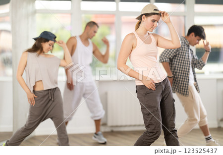 Group of energetic hip hop dancers focused on training while gathered together in spacious dance hall 123525437