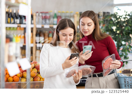 Mom and daughter scanning packages of hamburger patties Mom and daughter scanning packages of hamburger patties 123525440