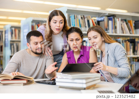 Group of students in the library is preparing for classes on a laptop 123525482