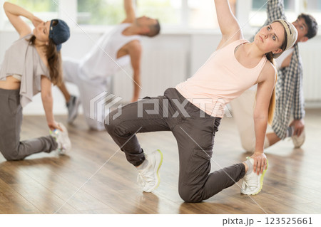Girl and her students perform hip hop dance on one bent leg, movement in horizontal plane near floor 123525661