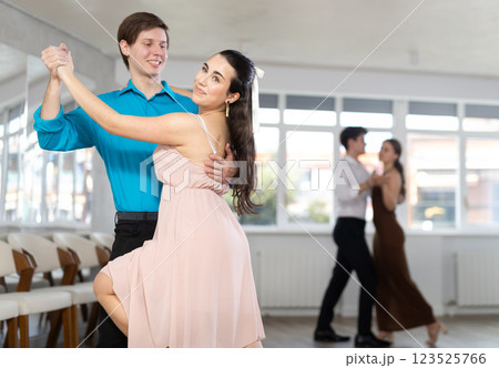 Couple in evening dresses enjoys pair dance tango, interacting with each other on floor Couple in evening dresses enjoys pair dance tango, interacting with each other on floor 123525766