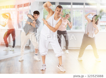 Young man standing performs basic hip hop movements in front of group of students 123525888