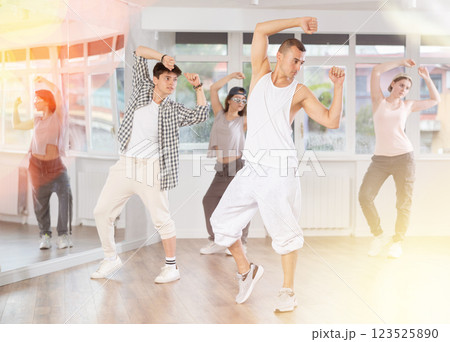 Young man standing performs basic hip hop movements in front of group of students Young man standing performs basic hip hop movements in front of group of students 123525890