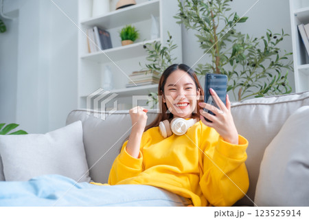 Smiling pretty young Asian woman sitting on cozy couch 123525914