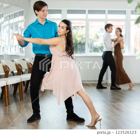 Smiling young brunette dancing tango with partner in dance studio Smiling young brunette dancing tango with partner in dance studio 123526123