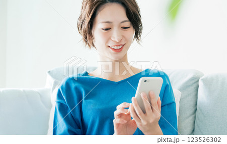 寝転んでスマホを見る若い女性 123526302