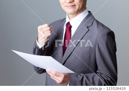 資料を持ってガッツポーズをするミドル男性ビジネスマン 123526420