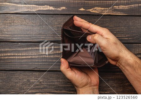 Struggling businessman looks at empty wallet in despair during financial crisis Struggling businessman looks at empty wallet in despair during financial crisis 123526560