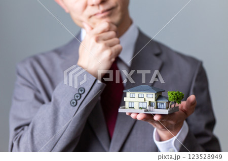 住宅模型を持って悩むミドル男性ビジネスマン 123528949